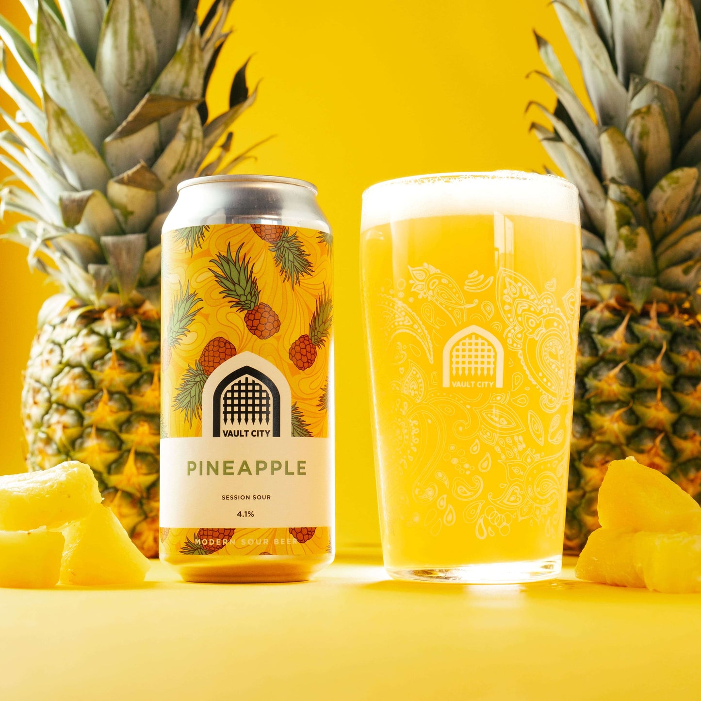 Pineapple Session Sour beer can and glass with fresh pineapple slices and whole pineapples in the background.