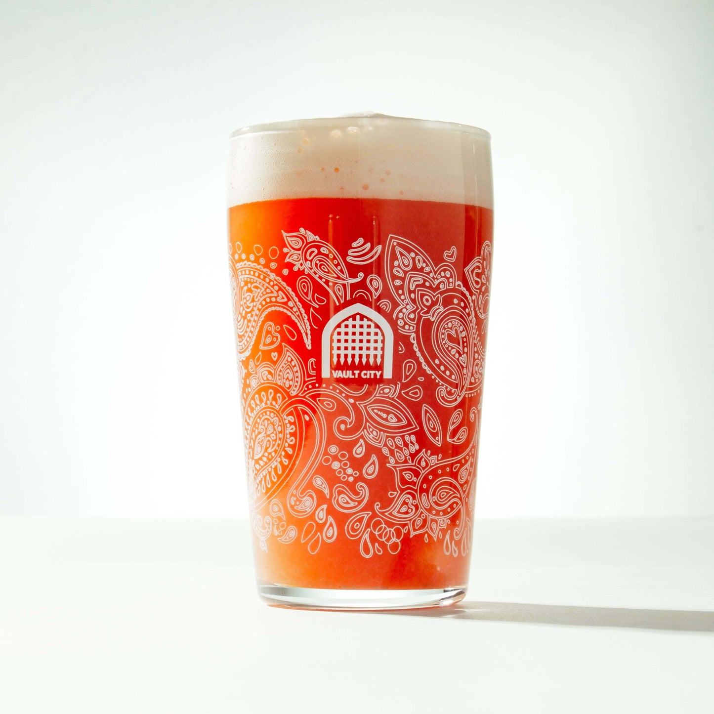 Vault City pint glass with paisley pattern droplet design, filled with beer