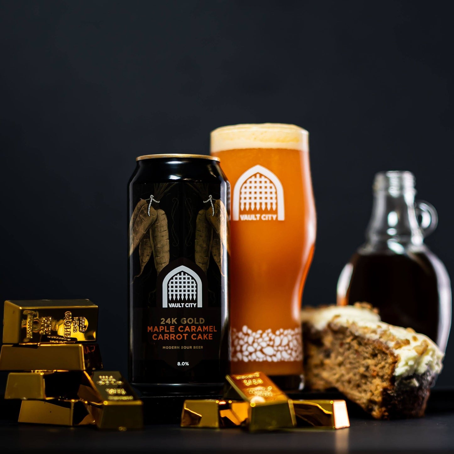 24K Gold Maple Caramel Carrot Cake beer with glass, carrot cake slice, maple syrup, and gold bars in a luxurious presentation.