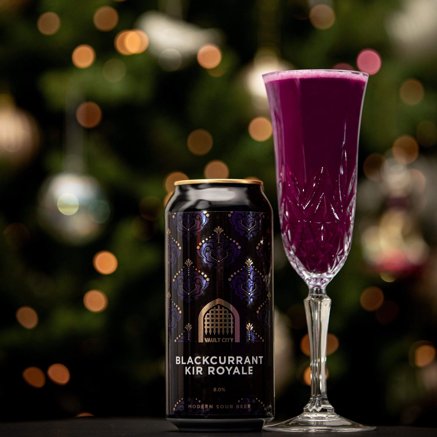 Can and glass of Blackcurrant Kir Royale sour beer elegantly displayed with a bokeh background.