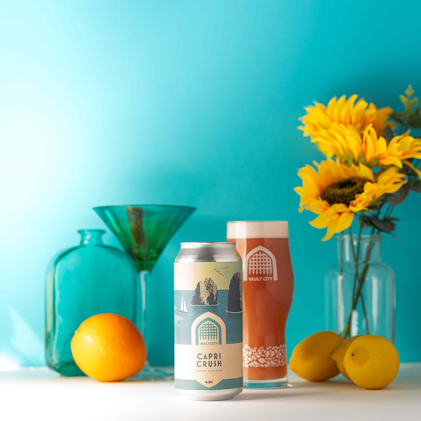 Can and glass of Capri Crush session sour beer with sunflowers and citrus fruits on a summer-themed background.