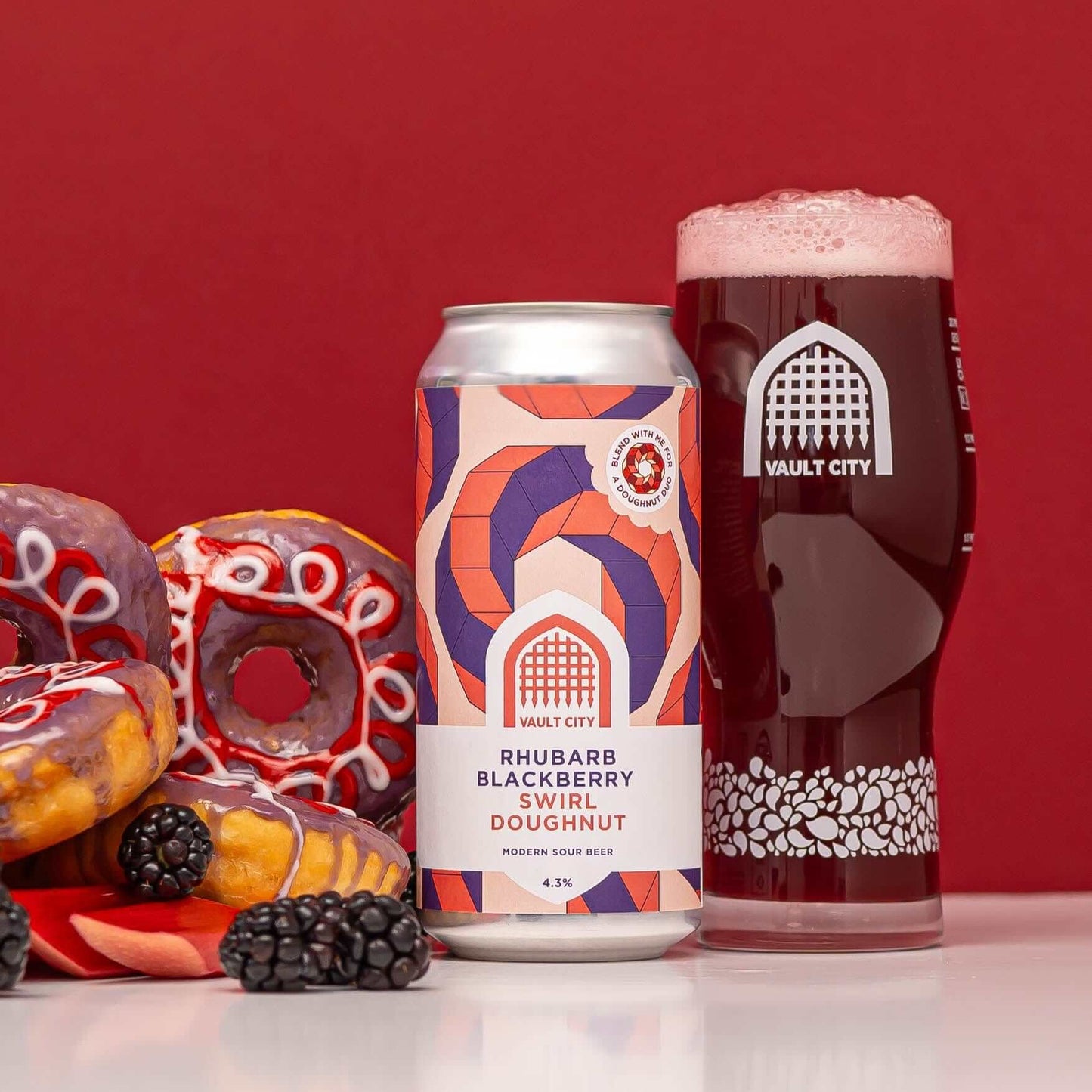 Can of Rhubarb Blackberry Swirl Doughnut sour beer with a glass of beer and decorated doughnuts on a red background.