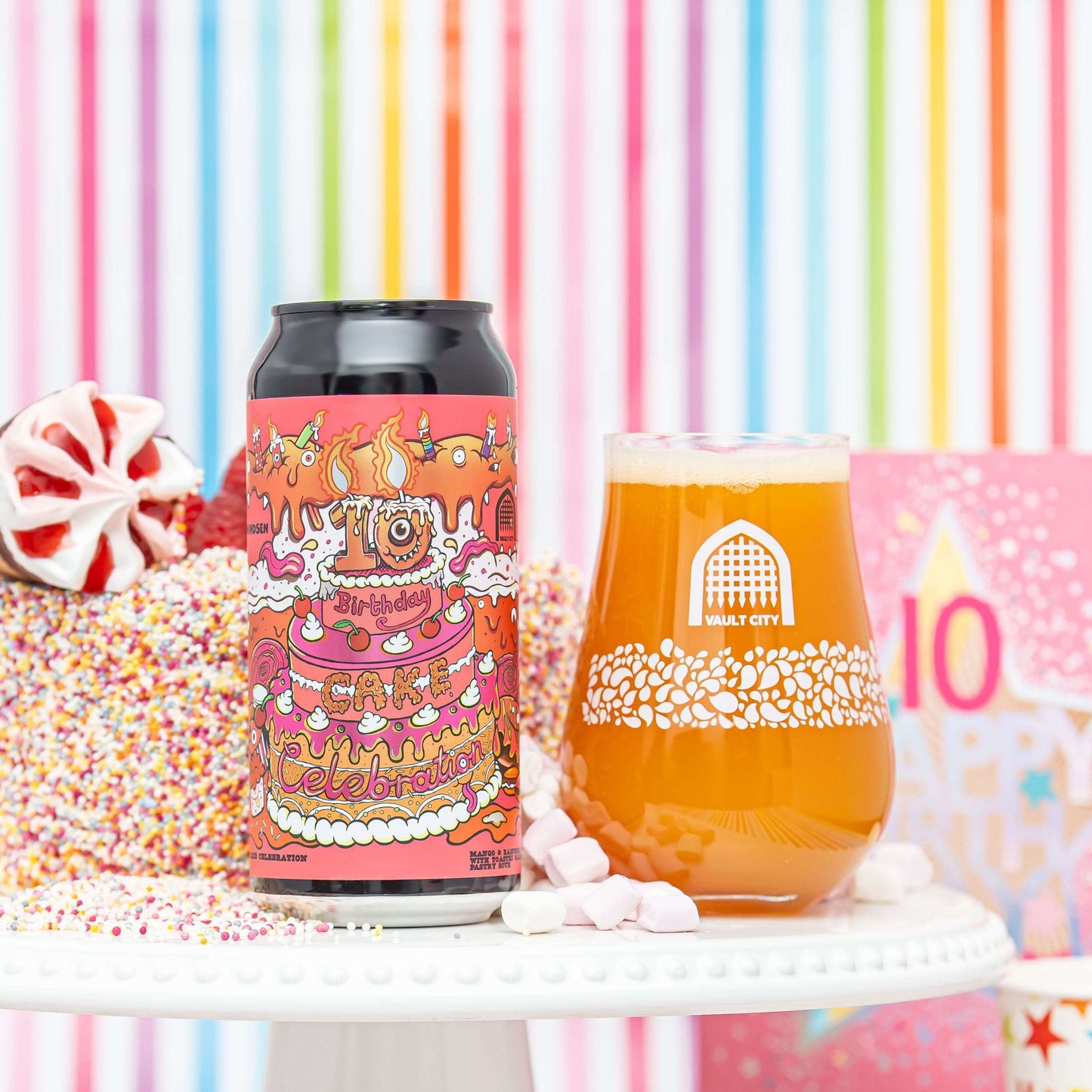 Celebratory Mango Raspberry Ice Cream Cake beer with can and glass, featuring toasted marshmallow swirl and sprinkles, striped backdrop