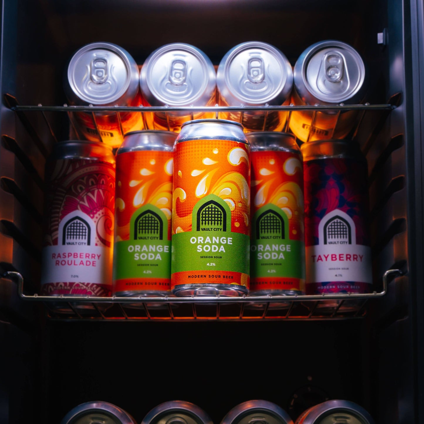 Vault City Orange Soda Session Sour cans displayed in a refrigerator with other flavored beverages.