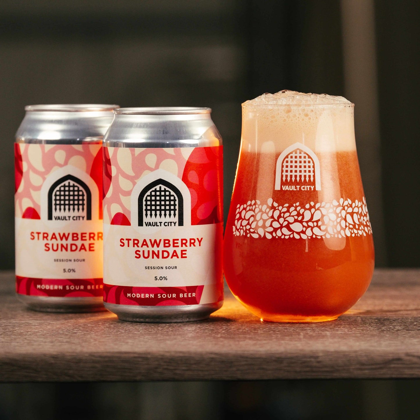Vault City Strawberry Sundae 330ml sour beer with fresh Scottish strawberry flavor in cans and glass on a wooden surface