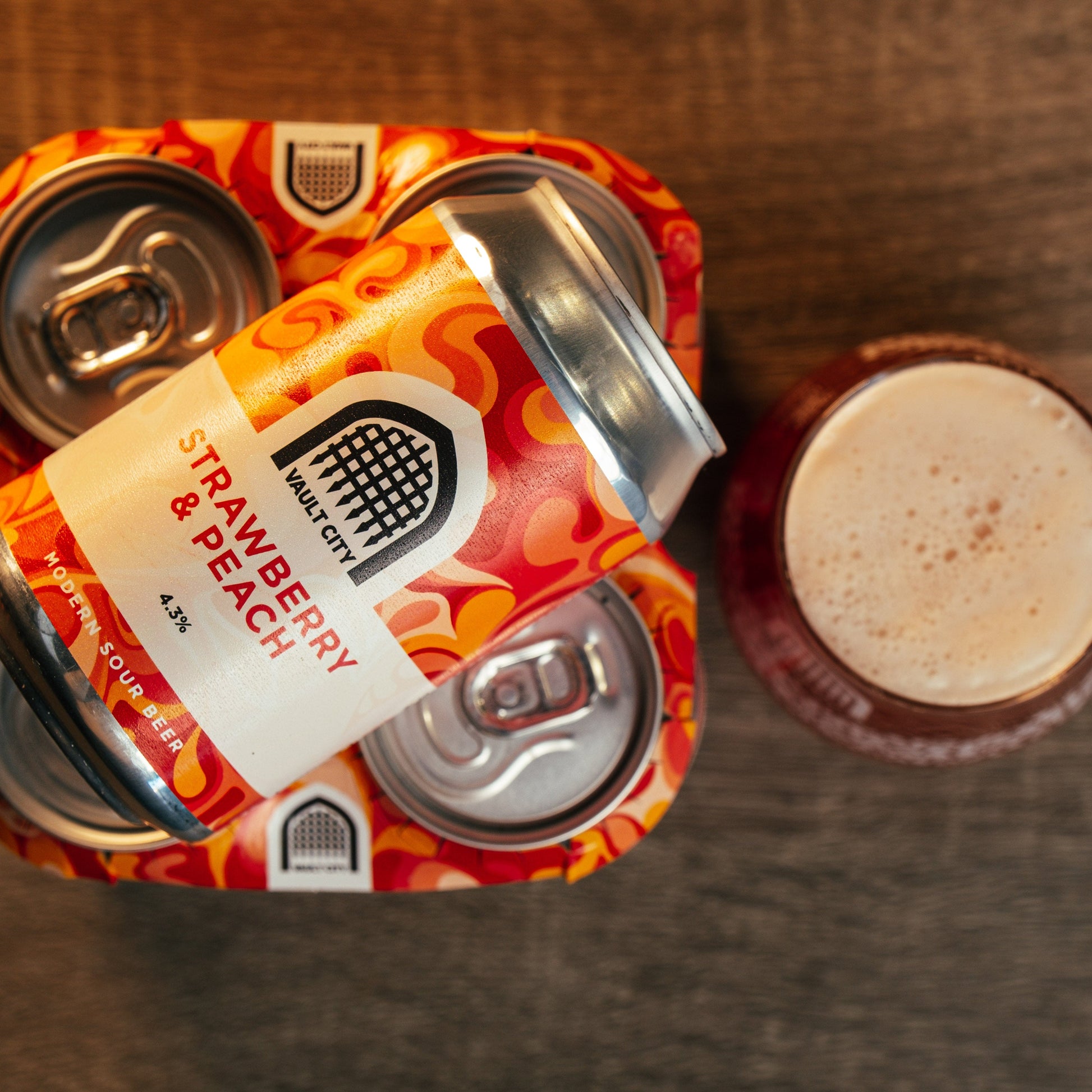 Strawberry & Peach 330ml cans, 4-pack, with a glass of foamy beer, showcasing a taste of summertime with juicy strawberries and succulent peaches.