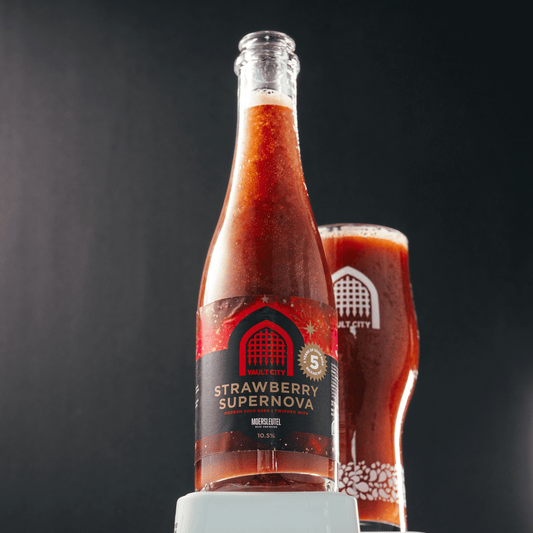 Bottle of Vault City x Moersleutel Strawberry Supernova beer with a glass, celebrating Vault City's 5th birthday, against a dark background