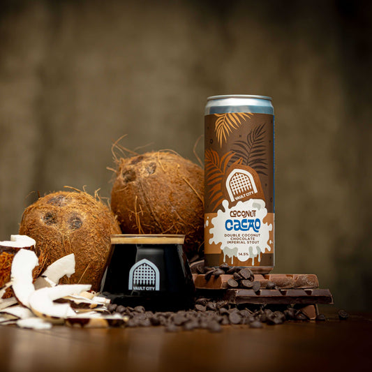 Can and glass of Coconut Cacao Imperial Stout with cacao nibs, coconut flakes, and whole coconuts in the background