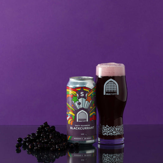 Tasty Rainbow Blackcurrant sour drink can and glass with blackcurrants against a purple background.
