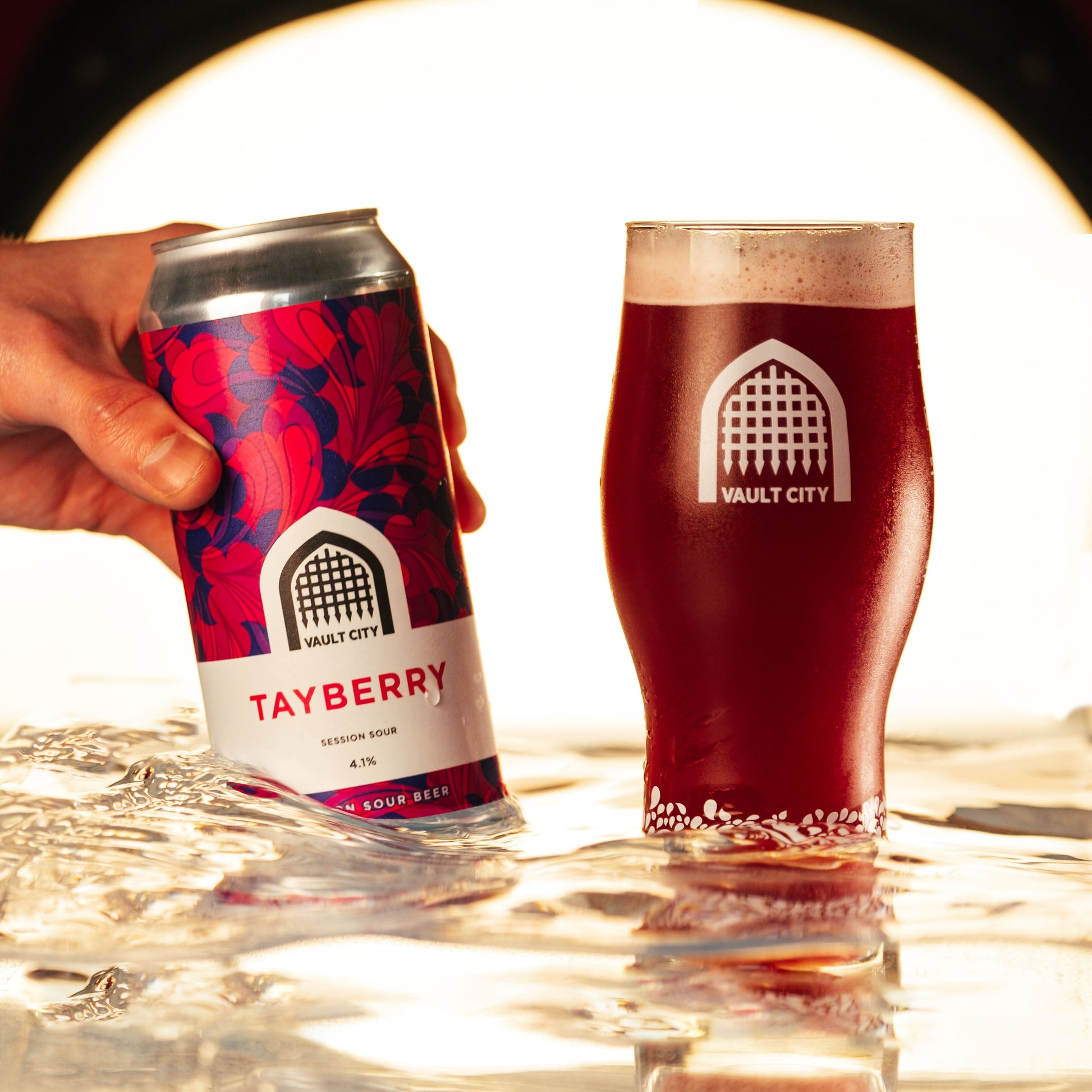 Tayberry Session Sour can and glass filled with golden sour ale, featuring Scottish tayberries, showcased on a reflective surface.